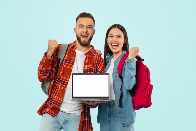 Um casal alegre mostrando a tela do laptop e fazendo gestos de sim ao estúdio