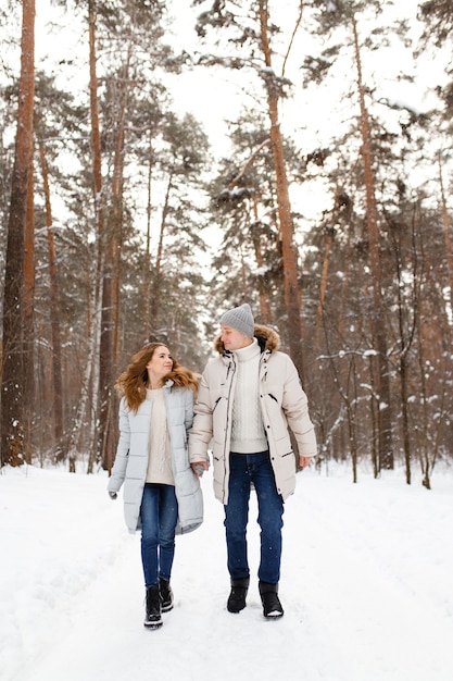 Um casal amoroso, alegre e feliz caminha na floresta de inverno