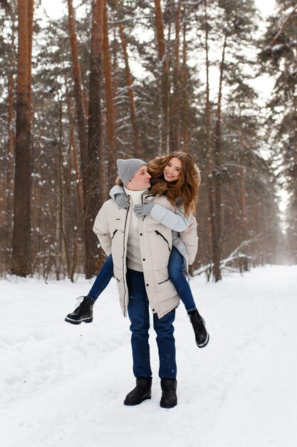 Um casal amoroso, alegre e feliz caminha na floresta de inverno