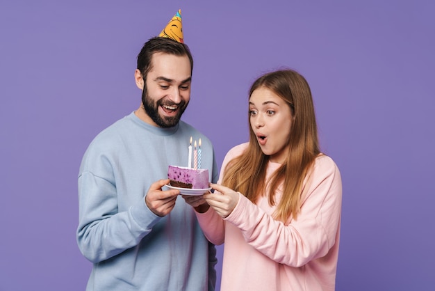 um casal amoroso jovem otimista positivo isolado sobre uma parede roxa com bolo de aniversário.