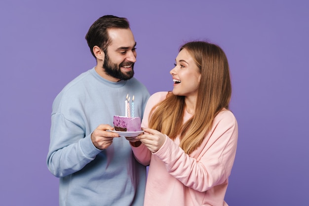 um casal amoroso jovem otimista positivo isolado sobre uma parede roxa com bolo de aniversário.