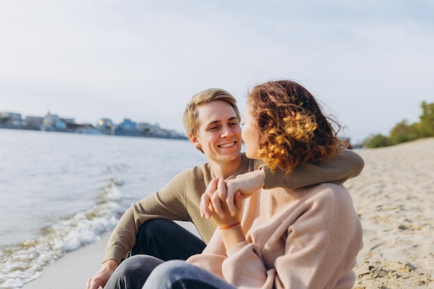 Um casal amoroso se diverte eles riem se abraçam e desfrutam de uma noite quente de verão Casal romântico sentado à beira-mar Retrato de um cara abraçando sua namorada