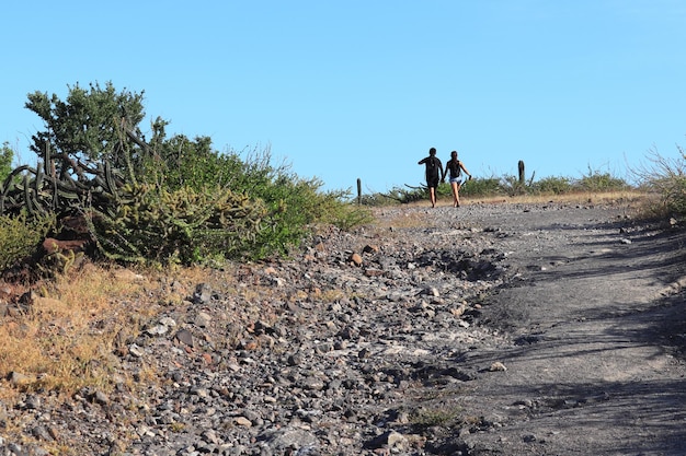 Um casal apaixonado de mãos dadas está caminhando em um terreno acidentado