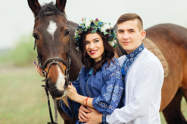 Um casal apaixonado em roupas festivas fica perto do cavalo