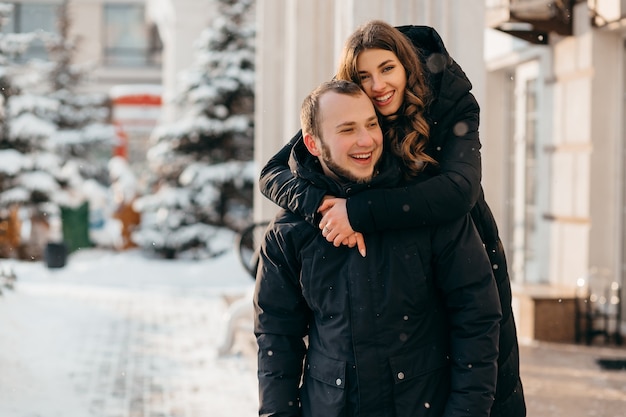 Um casal apaixonado em um abraço suave no contexto de uma cidade de neve. Foto de alta qualidade