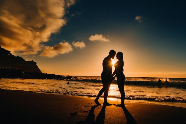 Um casal apaixonado está de pé na praia de mãos dadas ao pôr do sol O conceito de uma viagem romântica