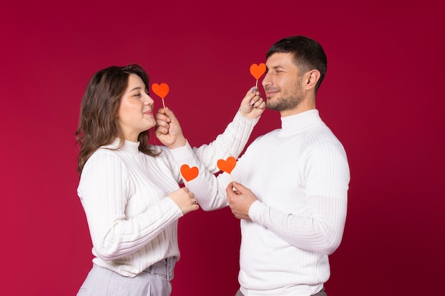 Um casal apaixonado posando com corações de papel vermelho sobre fundo vermelho. passar um tempo no dia dos namorados