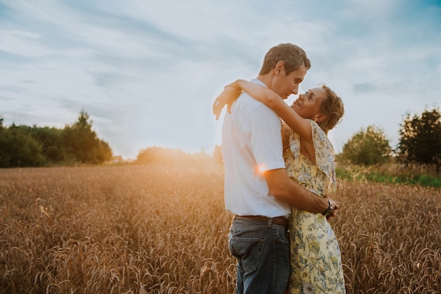 um casal apaixonado se abraça em um campo de trigo ao pôr do sol