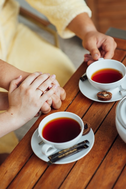 Um casal apaixonado se senta em roupão e bebe chá em uma mesa de madeira