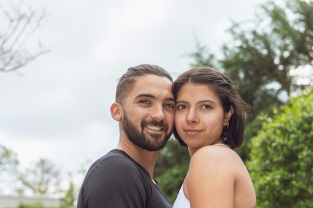 Um casal apaixonado se tocando olhando para a câmera ao ar livre