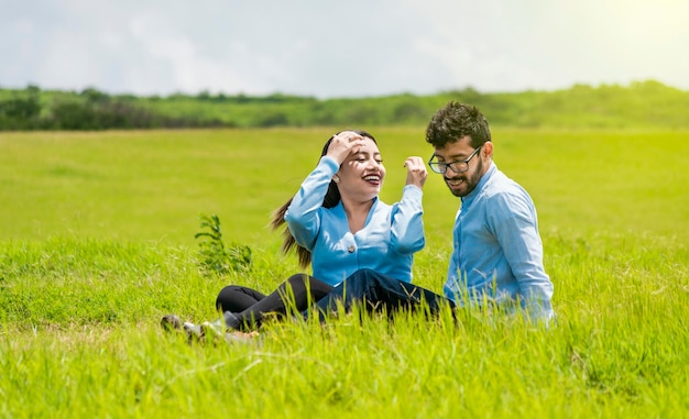 Um casal apaixonado sentado no campo Casal romântico sentado na grama ao ar livre Casal adolescente sorridente sentado na grama em um dia ensolarado