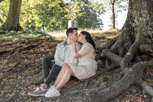 Um casal apaixonado, um casal e uma menina sentam-se debaixo de uma bela árvore e acariciam-se, beijam-se