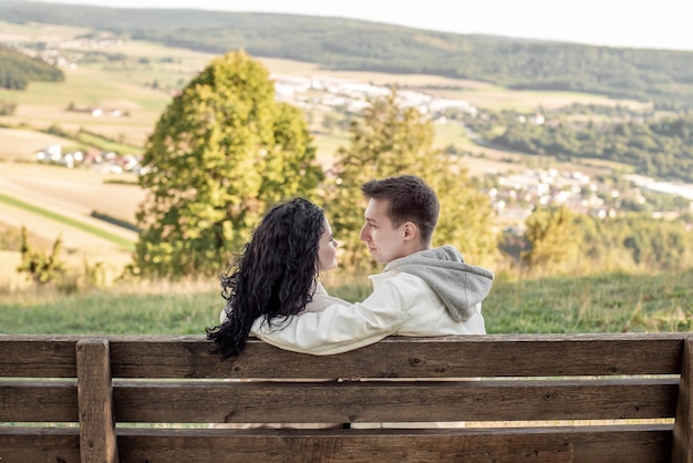 Um casal apaixonado, um rapaz e uma rapariga sentam-se num banco e acariciam-se, beijam-se