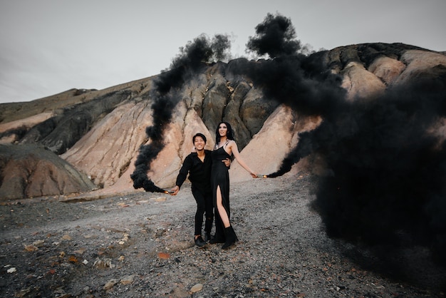 Um casal asiático apaixonado acendeu bombas de fumaça negra nas montanhas. Fumaça colorida