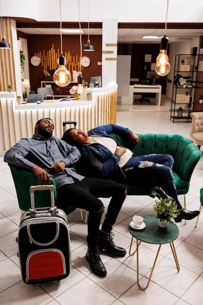 Foto um casal cansado a dormir uma sesta no átrio do hotel.