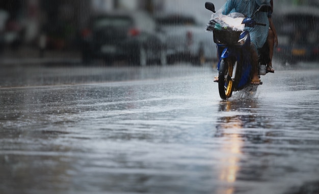 Um casal com capa de chuva em uma moto durante fortes chuvas. foco seletivo e composição de profundidade de campo muito rasa.