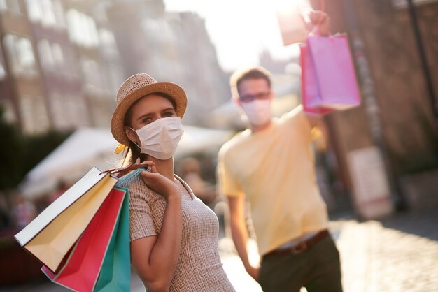 Um casal com sacolas de compras e máscaras protetoras devido ao coronavírus