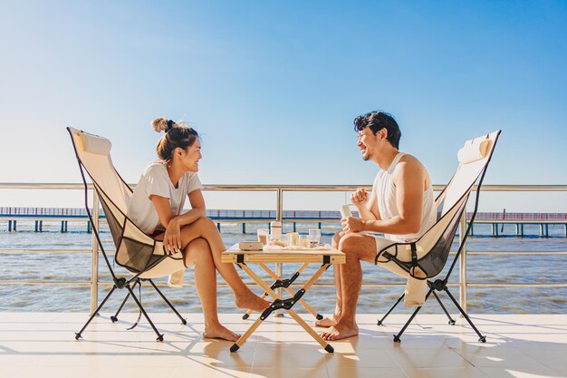 Um casal de amantes asiáticos desfruta de suas férias no mar no verão com um belo céu claro e vista para o oceano.