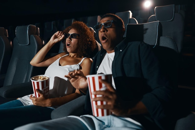 Um casal de amigos apaixonados assistindo a um filme com pipoca no cinema