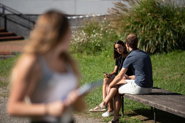 Um casal de estudantes universitários conversando enquanto uma garota ciumenta está olhando para eles