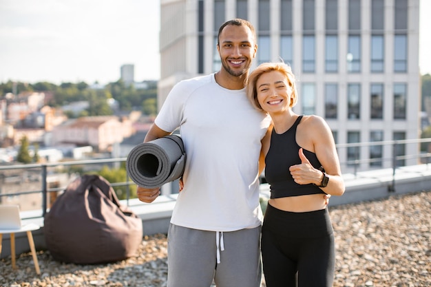 Foto um casal de fitness sorrindo em um telhado durante uma sessão de treino