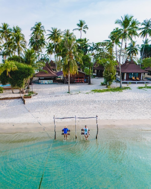 um casal de homens e mulheres em um balanço na praia de Koh Muk, na Tailândia