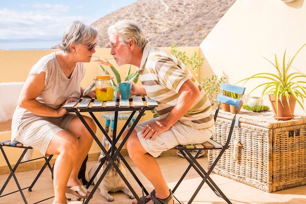Um casal de idosos a beber sumo num restaurante contra o céu.