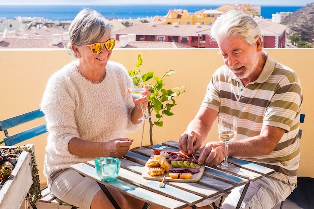 Um casal de idosos a desfrutar de vinho num restaurante ao ar livre