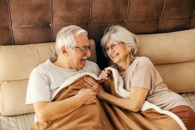 Um casal de idosos a ter momentos românticos na cama de manhã.