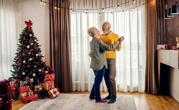 Foto um casal de idosos afetuosos está dançando no apartamento no natal e no ano novo.