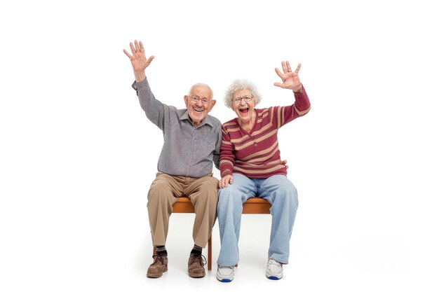 Um casal de idosos alegre sentado em um painel e acenando isolado em fundo branco