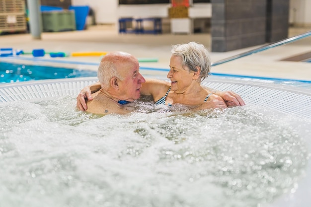 Um casal de idosos caucasianos a desfrutar do banho quente na piscina.