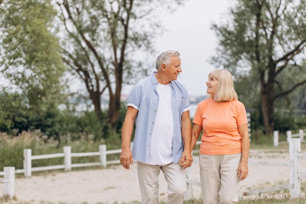 Um casal de idosos feliz caminhando de mãos dadas num parque