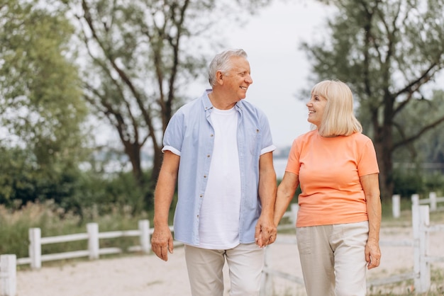 Um casal de idosos feliz caminhando de mãos dadas num parque
