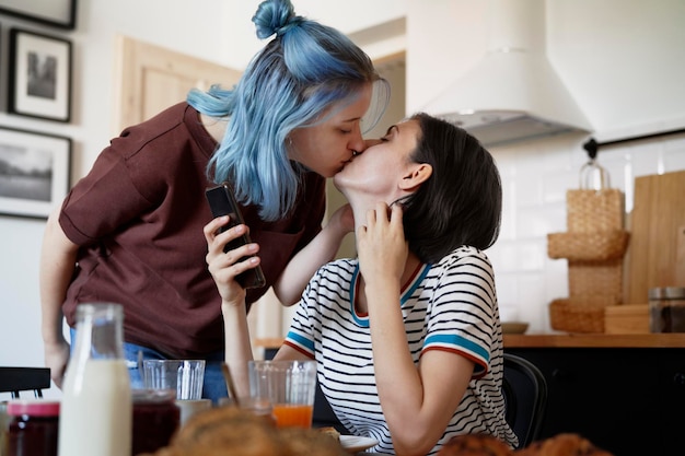 Um casal de lésbicas a beijar-se na cozinha.