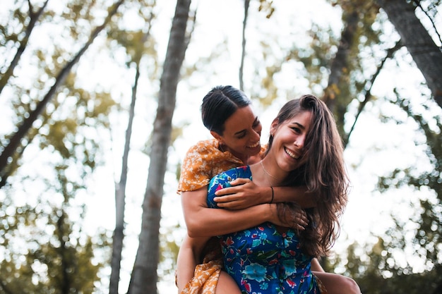 Um casal de lésbicas contra árvores na floresta.