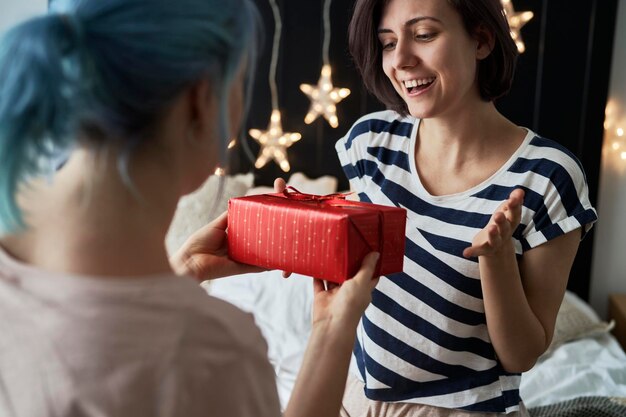 Foto um casal de lésbicas felizes a dar presentes de natal de manhã.