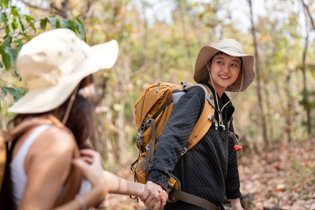 Um casal de lésbicas românticas e alegres viaja com uma mochila nas costas para fazer uma caminhada pela floresta nas montanhas no verão.