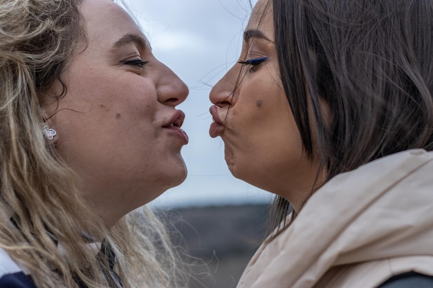 Um casal de lésbicas se beijando com lábios franzidos à noite ao ar livre