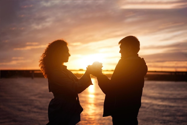 Foto um casal de mãos dadas e olhando o pôr do sol