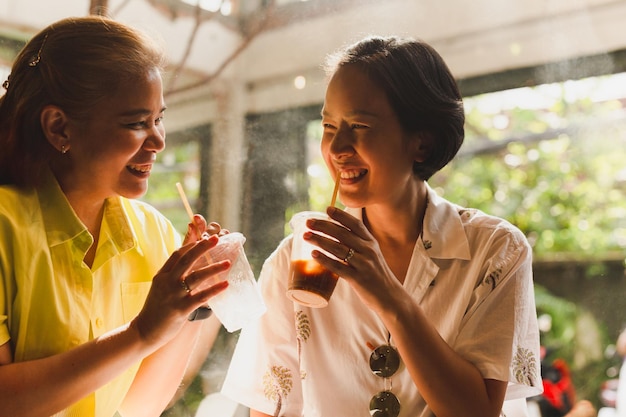 Um casal de mulheres felizes a sorrir a beber café num café.