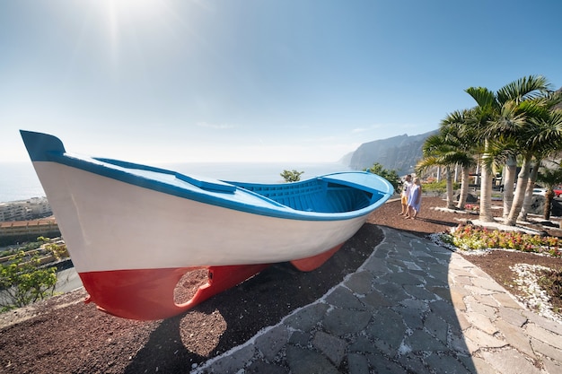 Um casal de namorados em um enorme barco, perto da praia nas falésias de acantilados de los gigantes, tenerife, espanha.