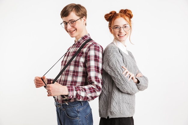 Foto um casal de nerds da escola sorrindo, costas contra costas