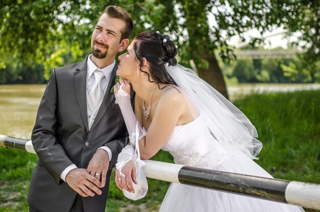 Foto um casal de noivas apoiado em um corrimão no parque