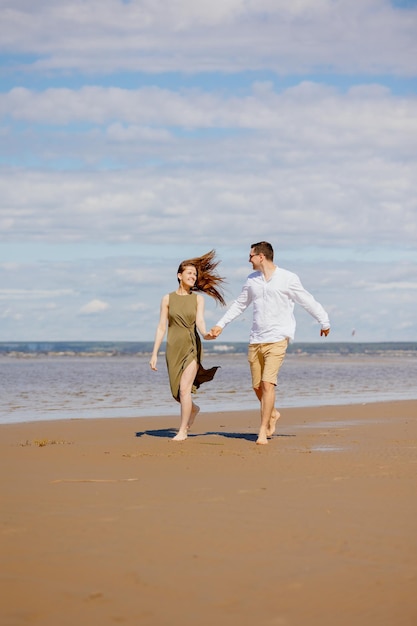 Um casal de um homem e uma mulher estão andando na praia ou correndo pela areia ao longo do