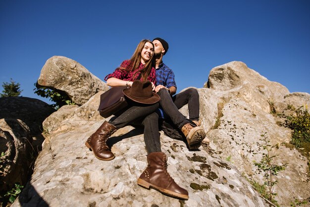 Um casal de viajantes hipster sentados juntos nas rochas nas montanhas