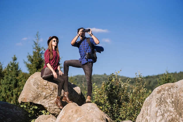 Um casal de viajantes juntos nas rochas nas montanhas sobre o fundo do céu azul