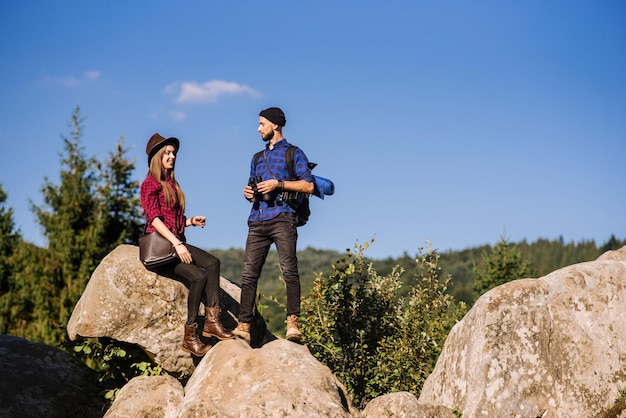 Um casal de viajantes juntos nas rochas nas montanhas sobre o fundo do céu azul