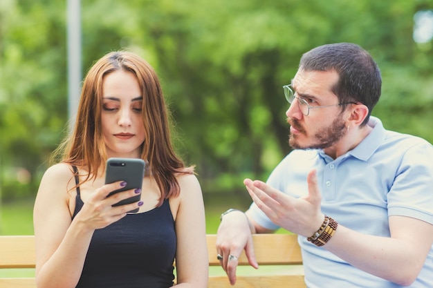 Um casal discutindo vê o homem está ditando que a mulher fique legal e despreocupada, olhando para o celular