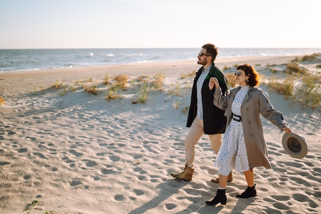 Um casal elegante a caminhar e a abraçar-se à beira-mar um lindo casal hipster a desfrutar do tempo juntos